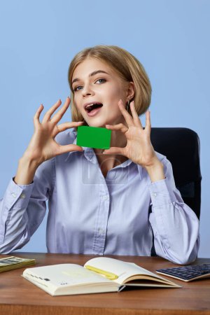 Téléchargez les photos : Femme d'affaires très excitée tenant carte de crédit en plastique sur fond bleu - en image libre de droit