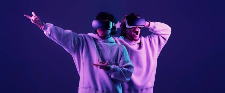 Foto de Hombre en sudadera con gafas de realidad virtual sobre fondo azul. Iluminación neón - Imagen libre de derechos