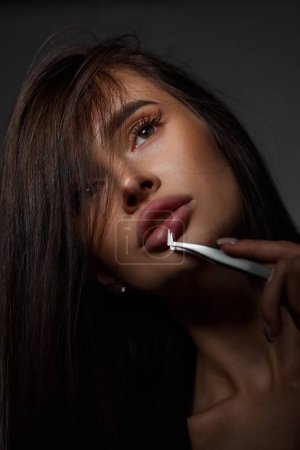 Photo for Beauty professional sexy woman holding tweezers while posing on black background. close-up - Royalty Free Image