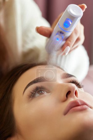 Photo for Cosmetologist using primer spray for eyelash extension procedure in salon - Royalty Free Image
