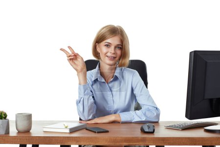 Téléchargez les photos : Succès blonde femme d'affaires regardant vers la caméra montrant les doigts faisant signe de victoire dans le bureau - en image libre de droit