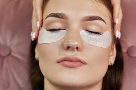 Photo for Cosmetologist preparing glue cotton strip under eye. Eyelash extension procedure - Royalty Free Image