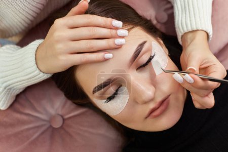 Photo for Cosmetologist removes glue cotton strip under eye. Eyelash extension procedure - Royalty Free Image