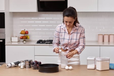 Téléchargez les photos : Femme préparant la pâte et craquant les œufs dans un bol à la cuisine - en image libre de droit