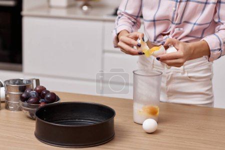 Téléchargez les photos : Mains féminines casser les œufs pour faire de la pâte pour la tarte, préparer la pâte à la cuisine - en image libre de droit