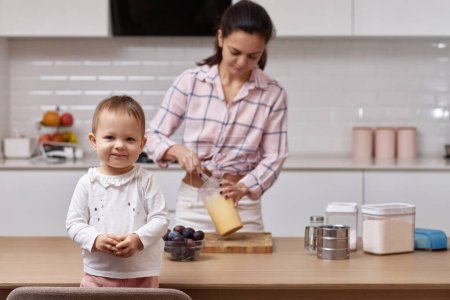Téléchargez les photos : Heureuse petite fille avec sa mère cuisinant à la cuisine. cuisiner ensemble - en image libre de droit