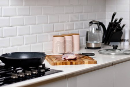 Foto de Cuchillo y carne fresca cruda sobre tabla de madera en la cocina moderna - Imagen libre de derechos