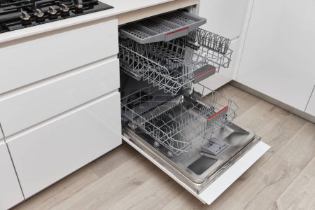 Téléchargez les photos : Lave-vaisselle vide intégré moderne avec porte ouverte dans la cuisine . - en image libre de droit