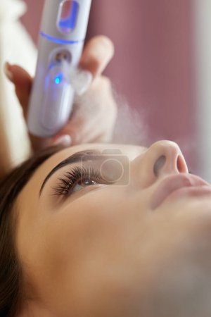 Photo for Cosmetologist using primer spray for eyelash extension procedure in salon - Royalty Free Image