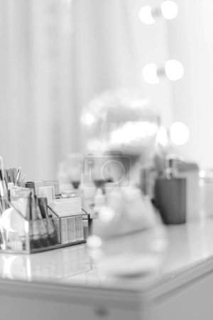 Téléchargez les photos : Table avec des cosmétiques décoratifs dans la salle de maquillage, noir et blanc - en image libre de droit