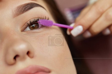 Photo for Master combs the eyelashes of the client after the eyelash extension procedure. close-up. Cosmetology and skin care - Royalty Free Image