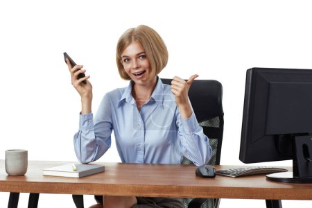 Téléchargez les photos : Jolie femme d'affaires blonde utilisant le téléphone et montrant les pouces geste dans le bureau - en image libre de droit