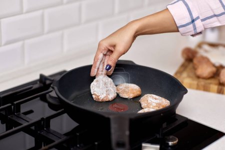 Foto de Manos femeninas preparando chuletas de carne caseras en cocina blanca - Imagen libre de derechos