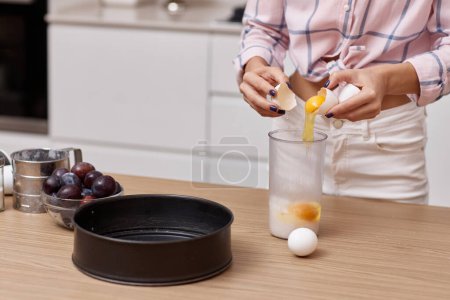 Téléchargez les photos : Mains féminines mélanger les œufs pour tarte aux prunes à la cuisine - en image libre de droit
