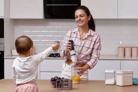 Téléchargez les photos : Mère heureuse avec sa petite fille cuisinant à la cuisine blanche. cuisiner ensemble - en image libre de droit