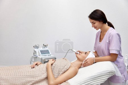 Téléchargez les photos : Cosmétologue faisant anti vieillissement procédure dans le salon de beauté. soins professionnels de la peau - en image libre de droit