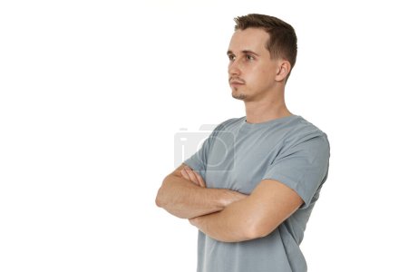 Téléchargez les photos : Profil de l'homme porte t-shirt tient les mains croisées isolé sur fond blanc - en image libre de droit
