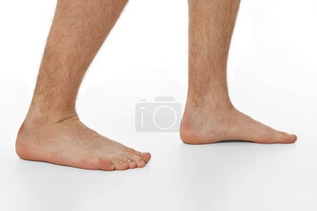 Téléchargez les photos : Pieds nus jambes masculines sur fond blanc. Concept de soins corporels. - en image libre de droit