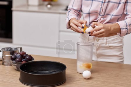 Photo for Female hands breaking eggs for baking at modern kitchen - Royalty Free Image