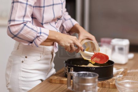 Téléchargez les photos : Femme au foyer pâtisserie tarte dans la cuisine moderne - en image libre de droit