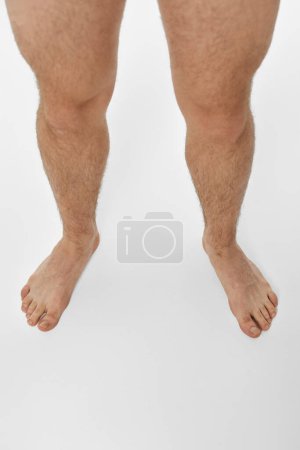 Téléchargez les photos : Pieds nus jambes masculines sur fond blanc. vue de dessus - en image libre de droit