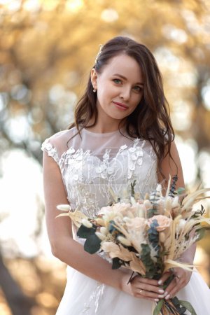 Téléchargez les photos : Belle mariée heureuse tenant mariage bouquet d'automne dans la nature - en image libre de droit