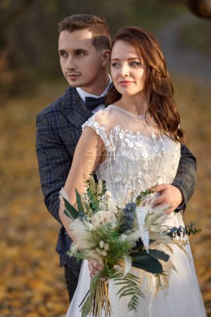 Téléchargez les photos : Belle mariée en robe blanche et marié câlin sur leur mariage - en image libre de droit