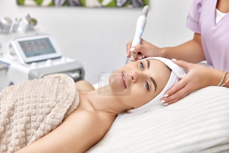 Photo for Cosmetologist making procedure microdermabrasion on the face in beauty salon - Royalty Free Image