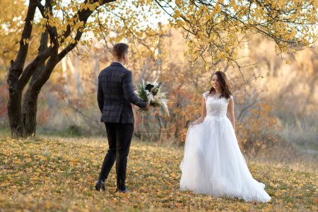 Foto de Hermosa novia sensual en vestido de novia blanco y novio de pie al aire libre sobre fondo natural - Imagen libre de derechos