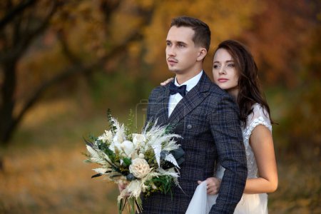 Téléchargez les photos : Belle mariée tenant bouquet et embrasser marié en plein air sur fond naturel - en image libre de droit