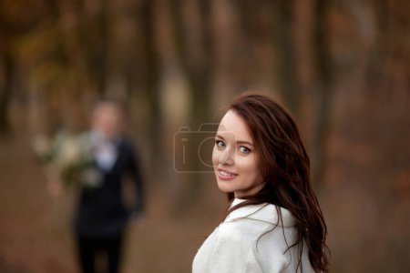 Photo for Portrait of beautiful happy bride and blur groom holding wedding autumn bouquet on the background - Royalty Free Image
