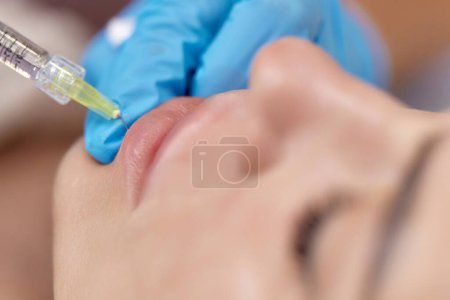 Téléchargez les photos : Cosmétologue fait des injections pour agrandir les lèvres de la belle femme. procédure augmentation des lèvres - en image libre de droit