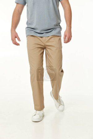 Photo for Man wearing white sneakers and casual beige pants and walking on studio background - Royalty Free Image