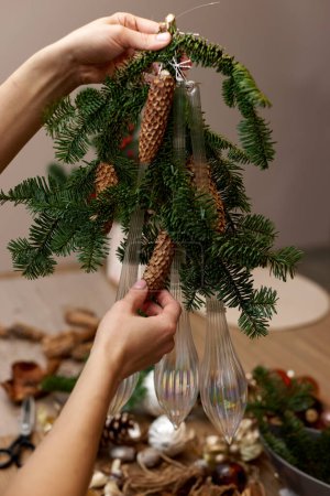 Photo for Woman making Christmas arrangement with fir branches, pine cones and bow. craft handmade decor. - Royalty Free Image