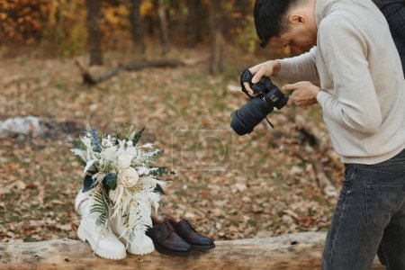 Photo for Wedding photographer taking pictures of bride and groom shoes, wedding bouquet outdoor. - Royalty Free Image