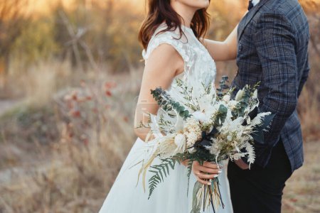 Téléchargez les photos : Mariée et marié tenant beau bouquet dans la nature en automne - en image libre de droit