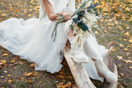 Photo for Bride wearing white boots holding beautiful autumn bouquet. copy space - Royalty Free Image