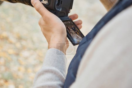 Téléchargez les photos : Photographe de mariage professionnel tenant caméra contre mariée et marié - en image libre de droit