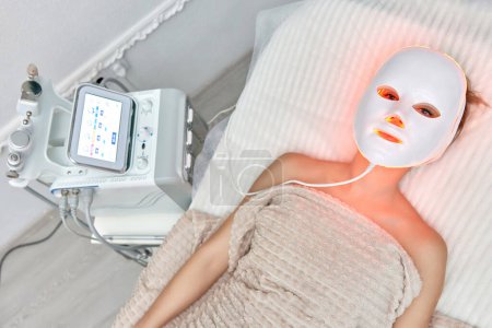 Foto de Mujer se encuentra con la máscara facial de terapia de luz led en el salón de belleza - Imagen libre de derechos