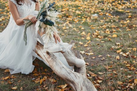 Photo for Bride wearing white boots holding beautiful autumn bouquet. copy space - Royalty Free Image