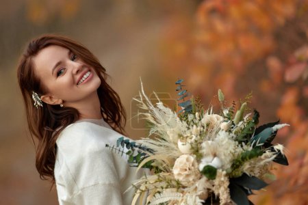 Foto de Retrato de hermosa novia feliz celebración de la boda ramo de otoño en la naturaleza - Imagen libre de derechos