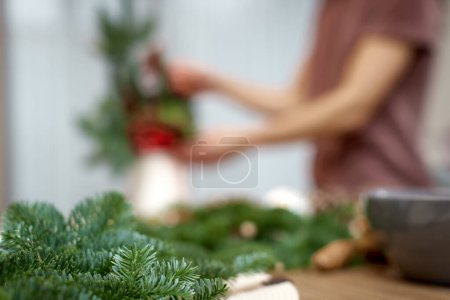 Téléchargez les photos : Fond flou de femme faisant arrangement de Noël avec des branches de sapin. focus sur branche sapin - en image libre de droit
