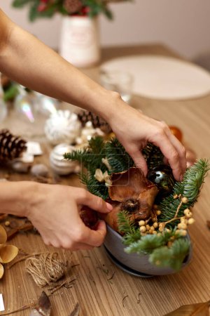 Foto de Mujer haciendo arreglos navideños con ramas de abeto. artesanal decoración hecha a mano. - Imagen libre de derechos