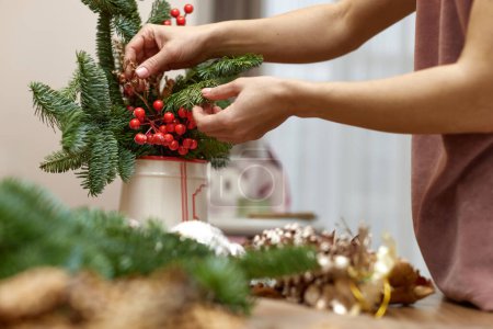 Téléchargez les photos : Femme faisant des arrangements de Noël avec des branches de sapin. décor artisanal. - en image libre de droit