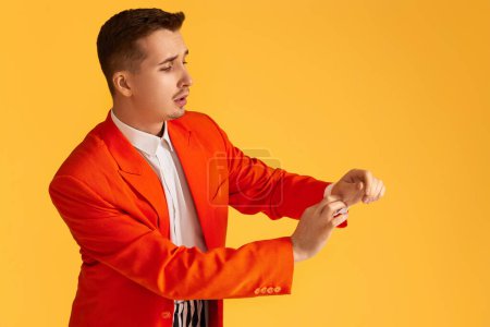Téléchargez les photos : Jeune homme à la mode en veste orange et pantalon rayé sur fond jaune. - en image libre de droit