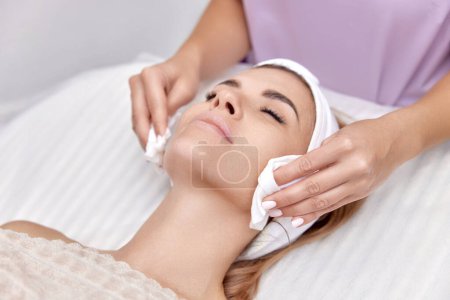 Photo for Beautician cleanses skin of beautiful woman with sponge. Perfect cleaning, spa treatment skincare face. - Royalty Free Image