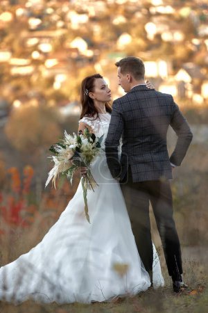 Foto de Retrato de cuerpo entero de novia en vestido de novia blanco y novio de pie al aire libre sobre fondo natural - Imagen libre de derechos