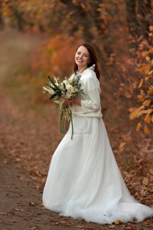Photo for Beautiful happy bride holding wedding autumn bouquet in nature - Royalty Free Image