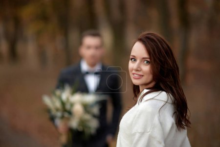 Foto de Retrato de hermosa novia feliz y novio borroso celebración de la boda ramo de otoño en el fondo - Imagen libre de derechos