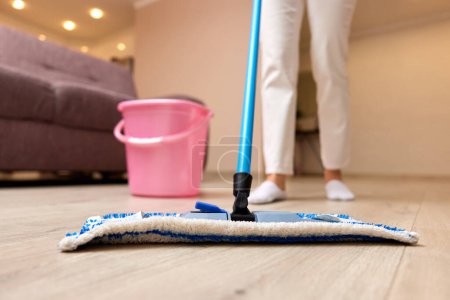 Téléchargez les photos : Jeune femme nettoyage sol avec balai humide à la maison, ménage quotidien, gros plan - en image libre de droit